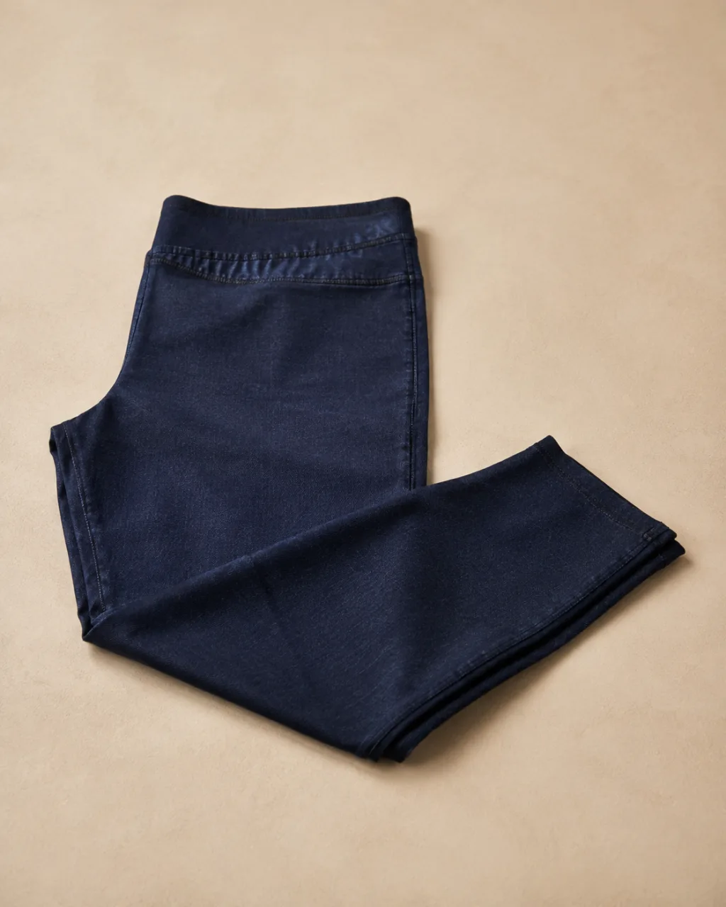 a pair of jeggings folded once at the knee and laid flat with a mid rise and a full elastic waistband , fabric: Cotton/polyester/spandex knit